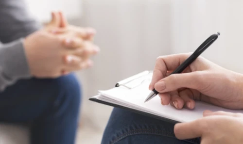 Therapeutin schreibt sich Anamnesepunkte auf