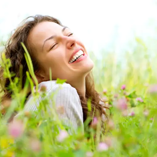 Glückliche Frau liegt lachend in einer Blumenwiese
